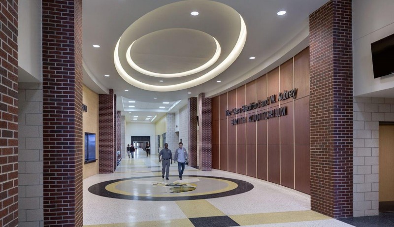 Denison High School learning hall with a curved specialty ceiling system and warm wood accents.